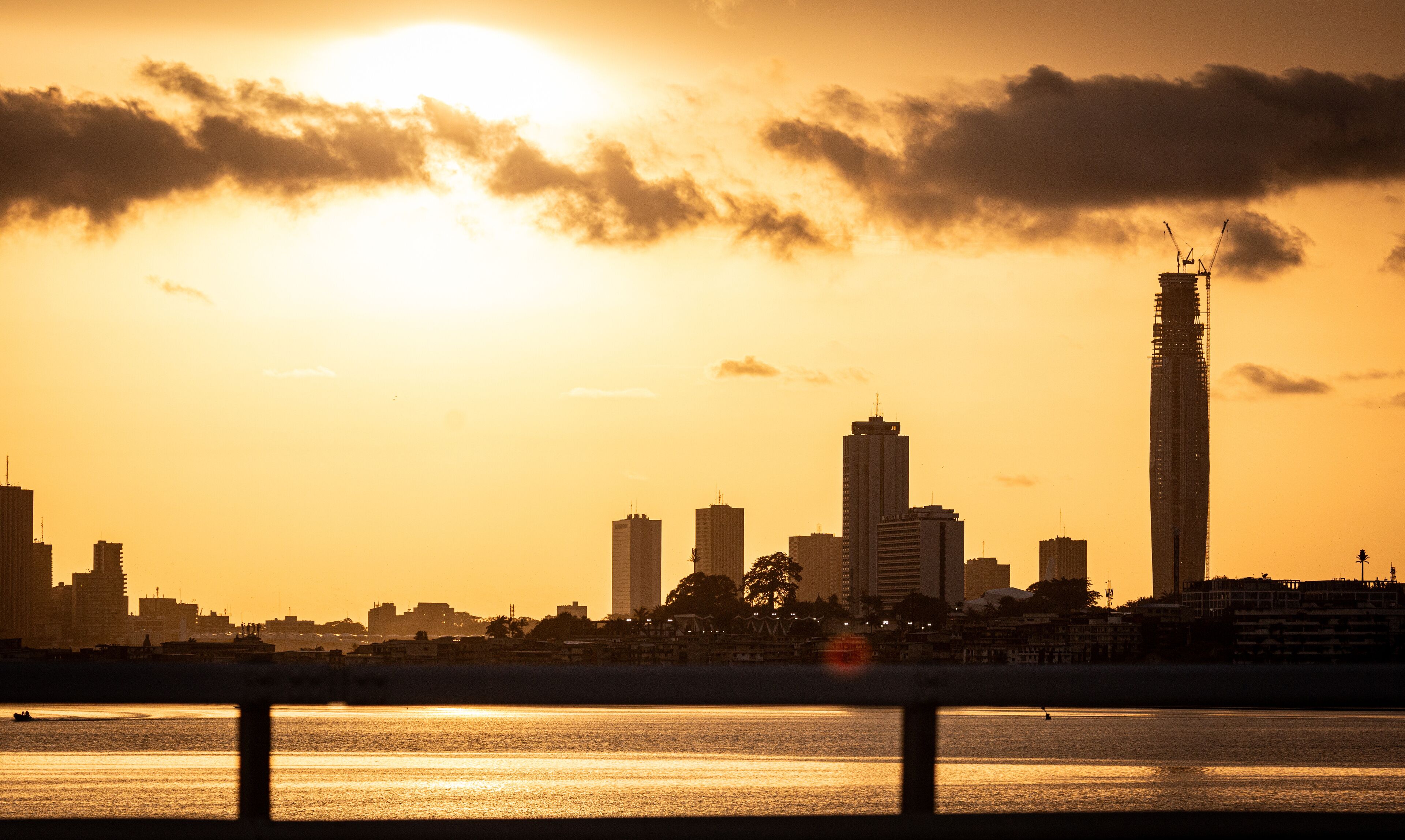 Abidjan at sunset featuring the iconic F Tower under construction, seen from across the Ébrié Lagoon. 2025.