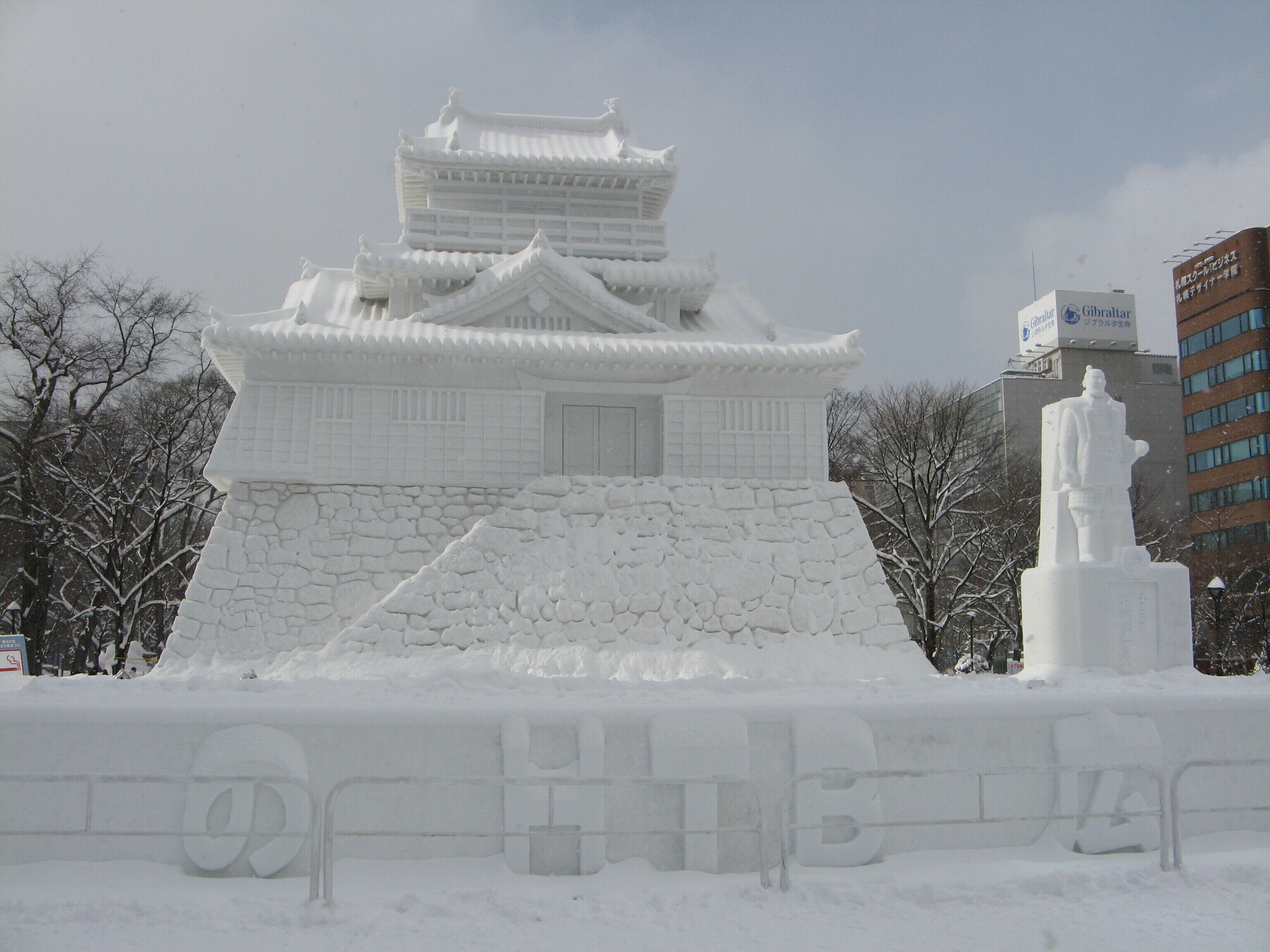 A snow-covered castle with a statue in front.
