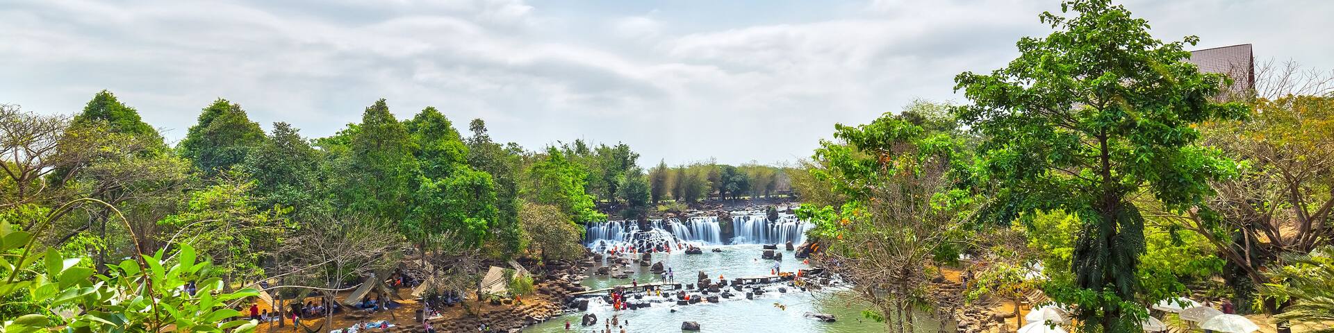 Giang Dien Waterfall above with water pouring down billowing white, surrounded by a forest covered attract many tourists to the resort, above the beautiful cloudy sky sunny day fresh welcome freshness