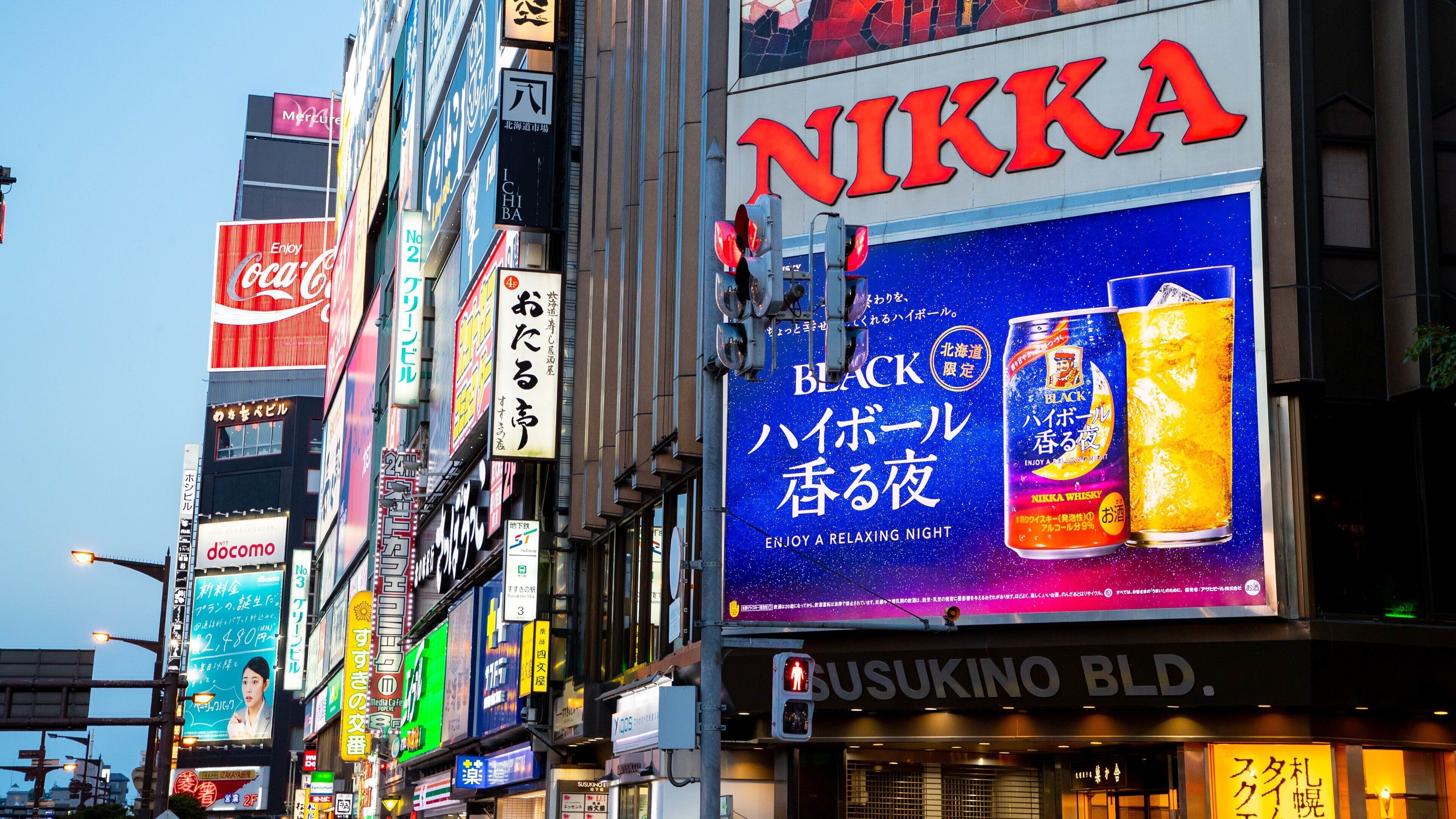 A busy urban street with numerous billboards and advertisements, including a prominent NIKKA whisky ad.