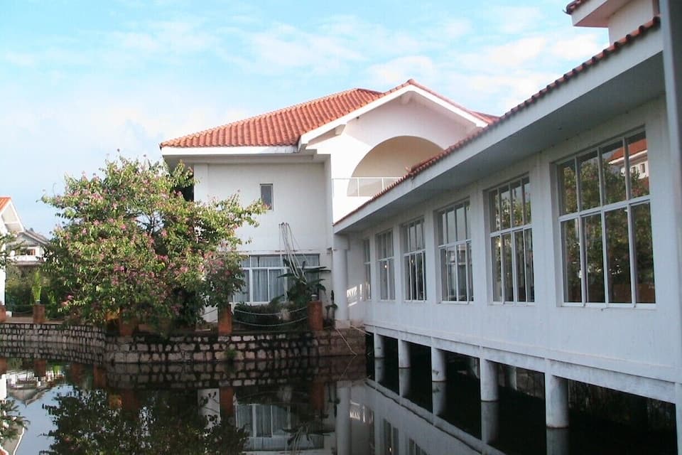 A traditional building with a tiled roof, a white exterior, and a reflection in the water.