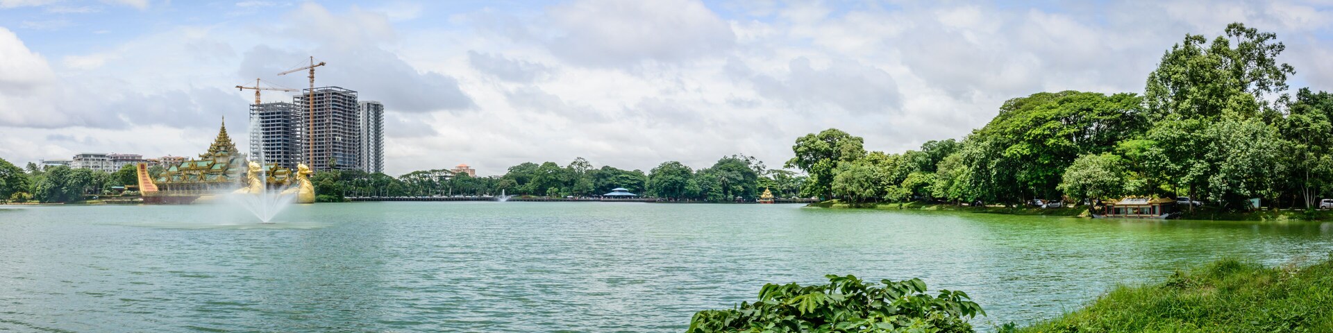 Um lago com uma fonte, um pagode e uma grua de construção ao fundo.
