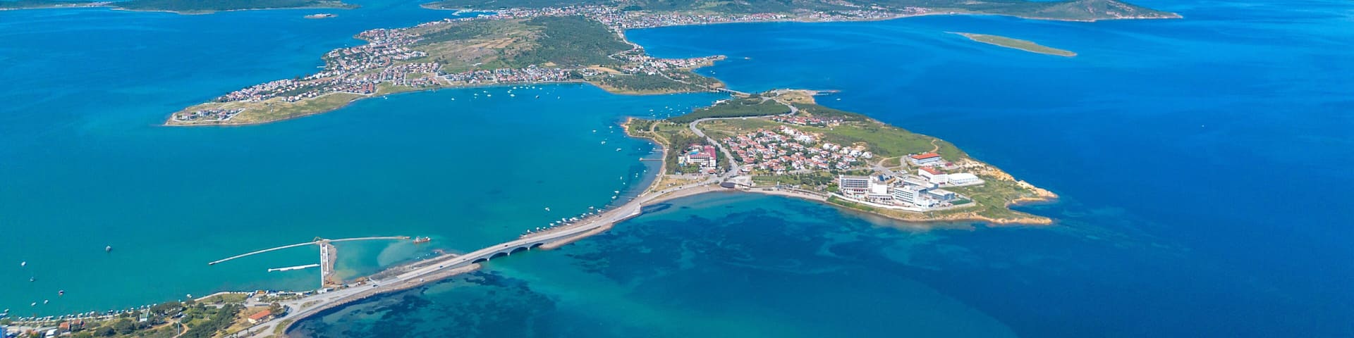 An aerial view of a coastal city with a bridge, clear blue waters, and surrounding islands.