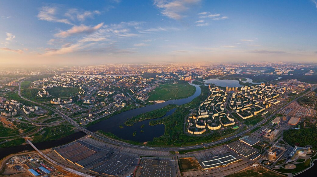 An aerial view of a city with a river, green spaces, and a large stadium.
