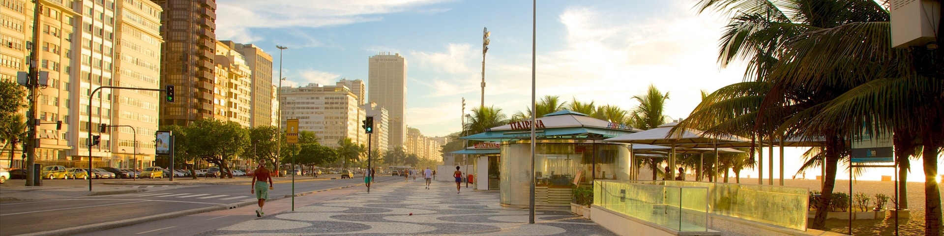 Uma praça urbana com padrões de paralelepípedos, palmeiras e edifícios modernos.