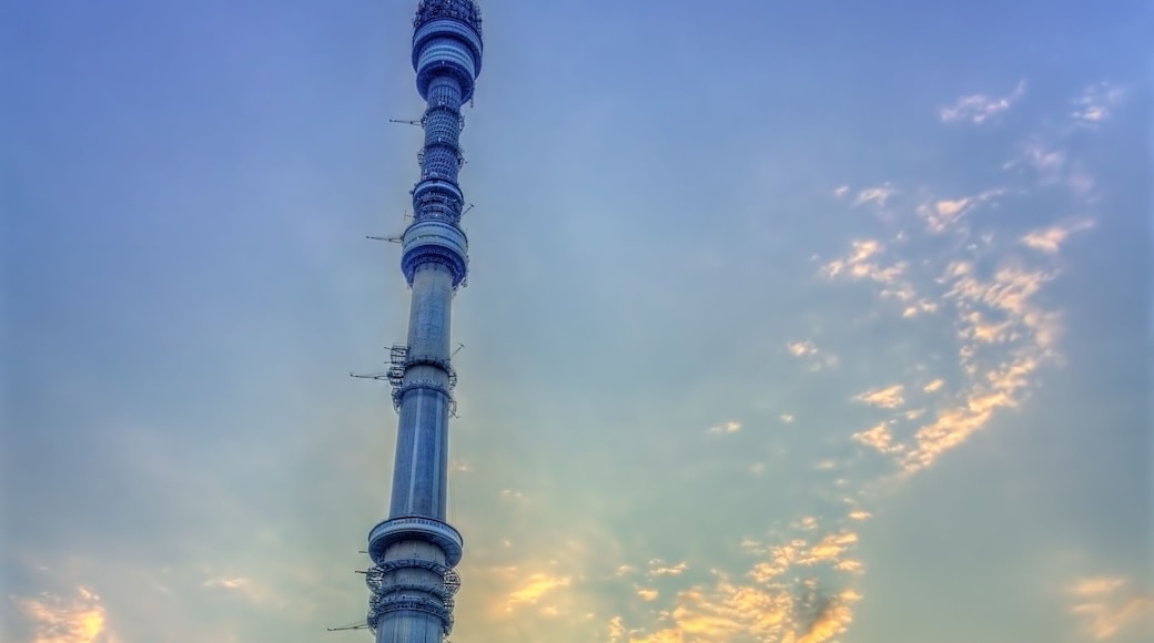 A tall tower with a spiral design, surrounded by a park with trees and a clear sky.