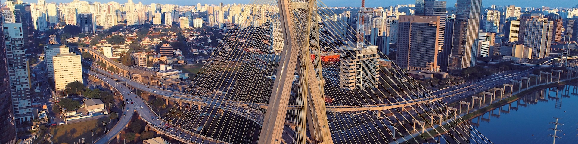 Uma ponte suspensa com um horizonte urbano ao fundo.