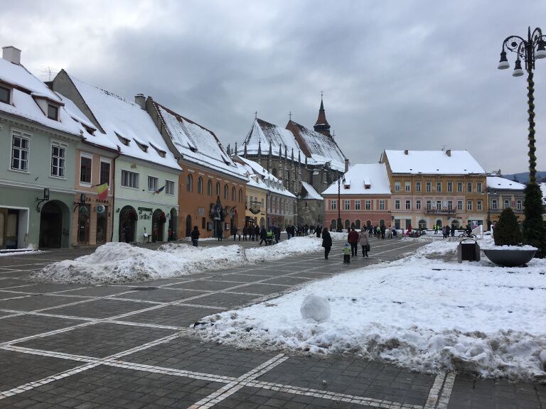 A snow-covered square with historic buildings and a cobblestone street.