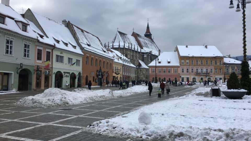 A snow-covered square with historic buildings and a cobblestone street.