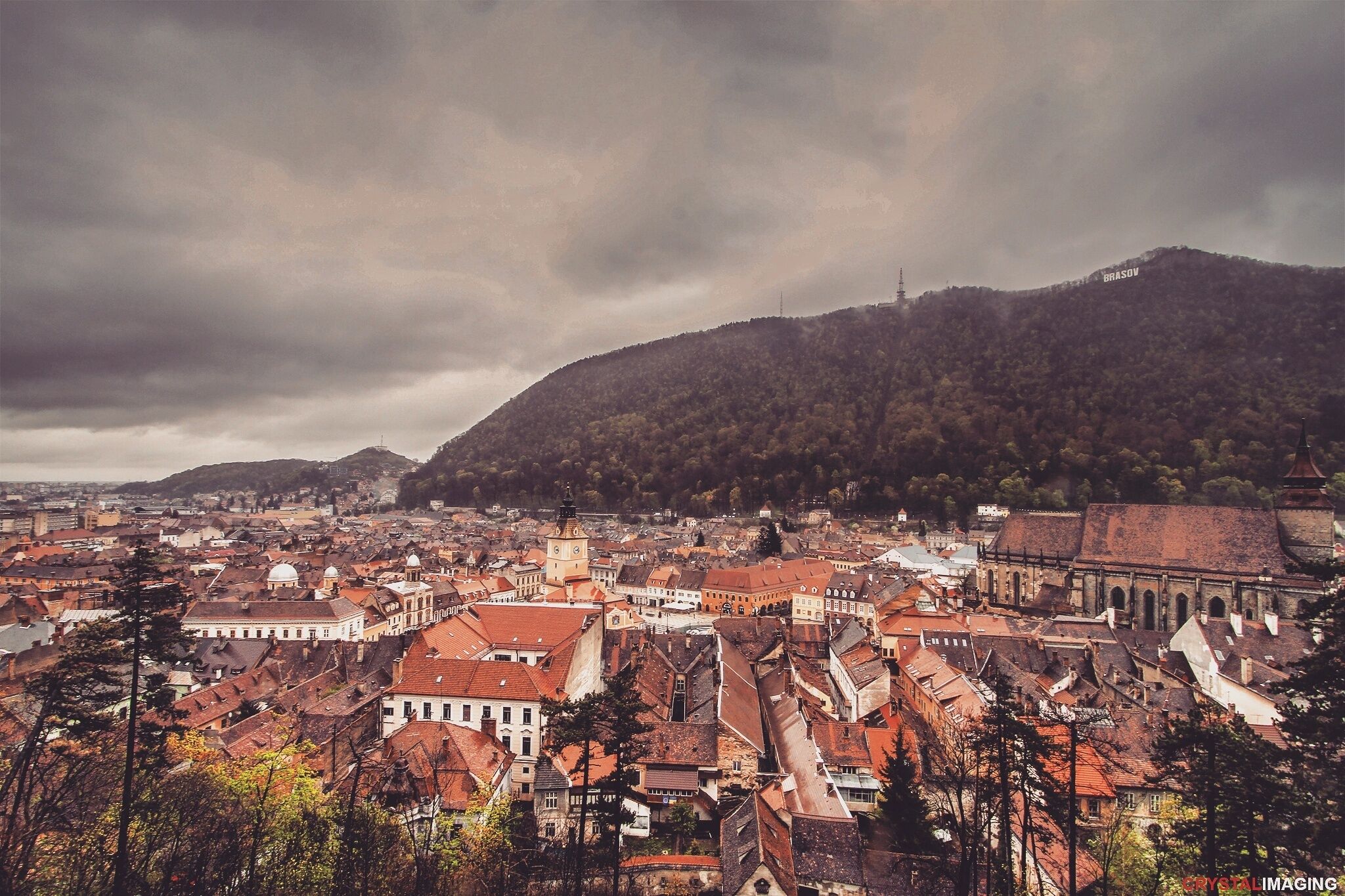 A cityscape with historic buildings and a large hill in the background.