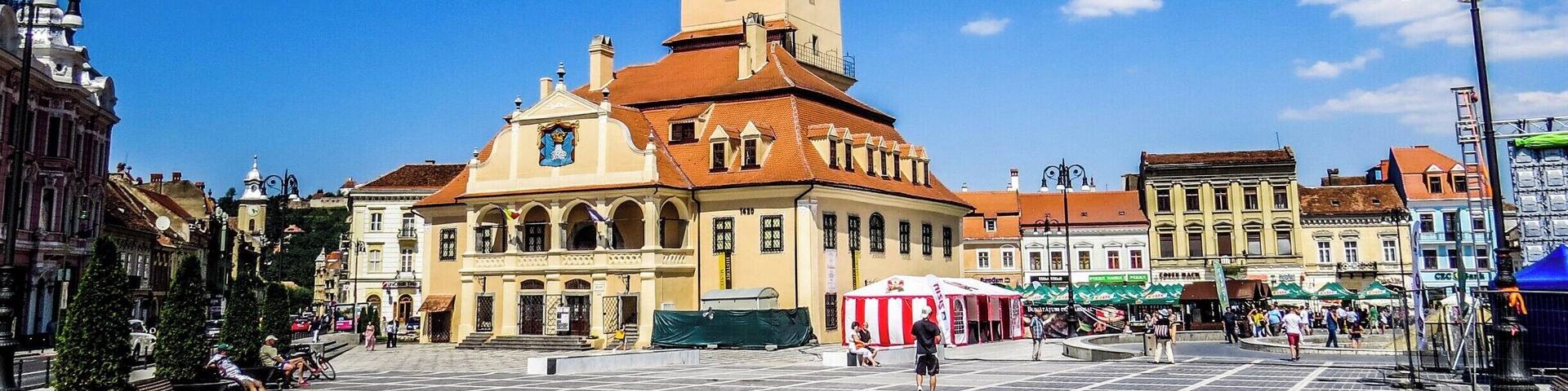 A historic square with a prominent clock tower, a large open plaza, and surrounding buildings.