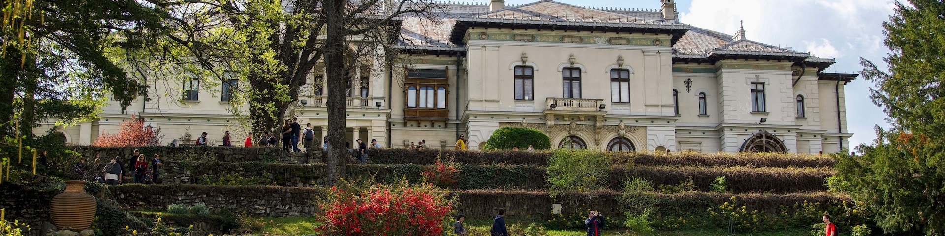 Un edificio histórico con jardín y una estatua.