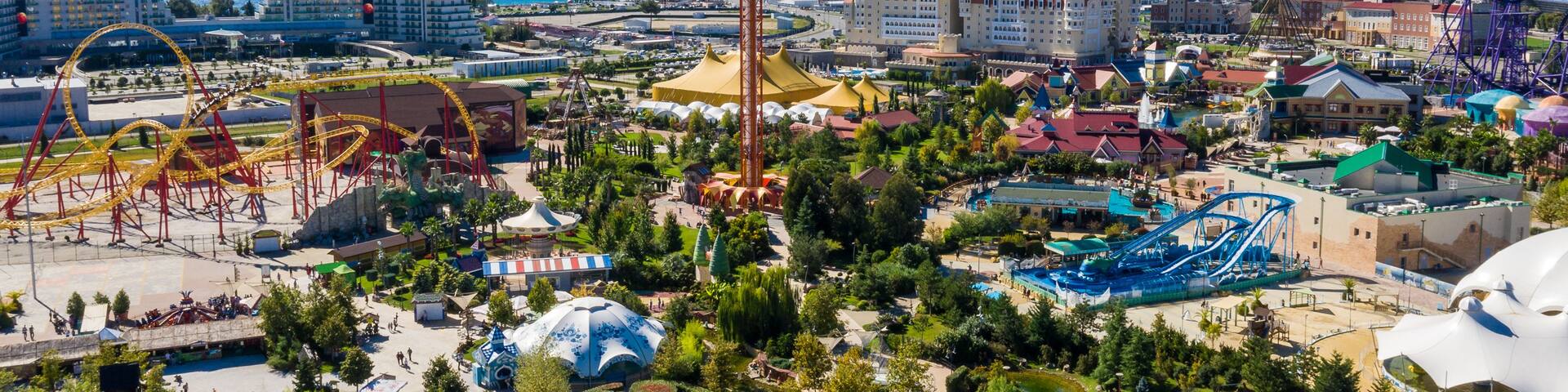 A theme park with roller coasters, a Ferris wheel, and a large white dome structure.