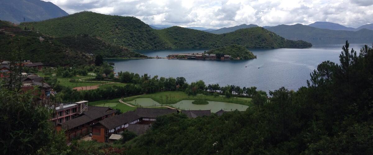 A lake surrounded by mountains, a golf course, and traditional buildings.