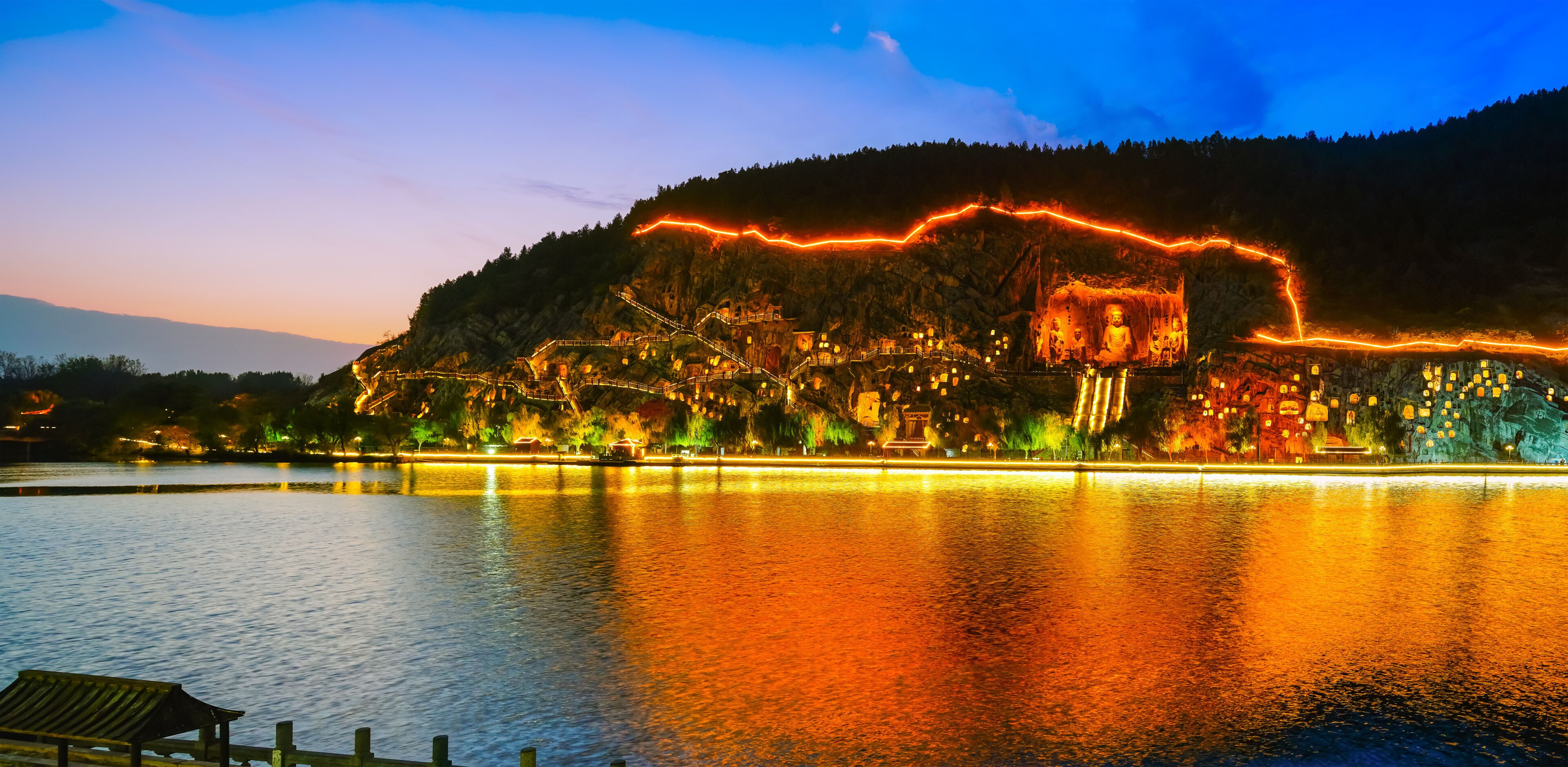 View of the historic Longmen Grottoes along the Yi River at sunset in Luoyang, China.