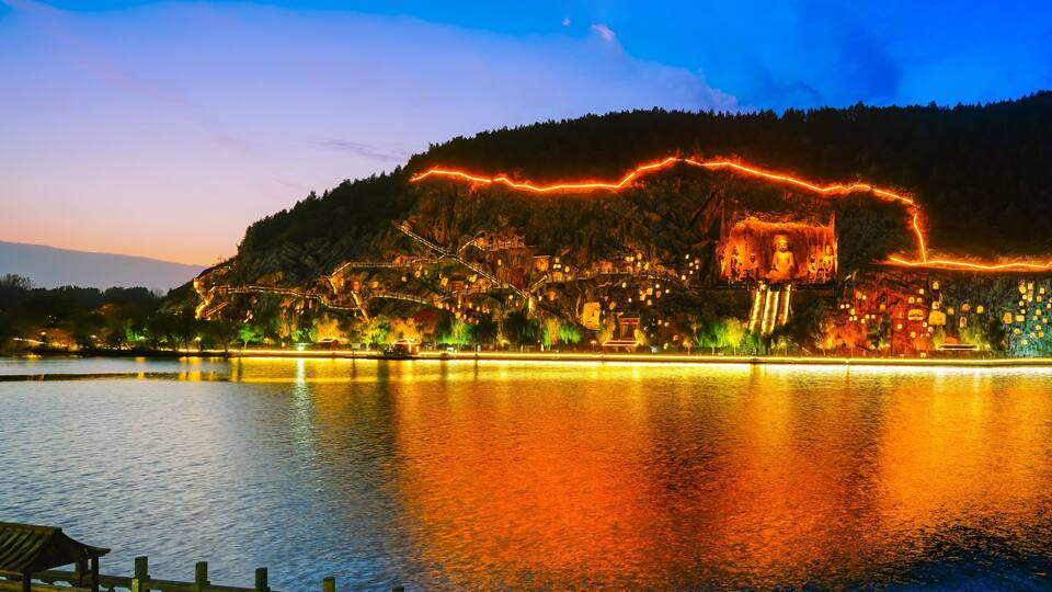 View of the historic Longmen Grottoes along the Yi River at sunset in Luoyang, China.