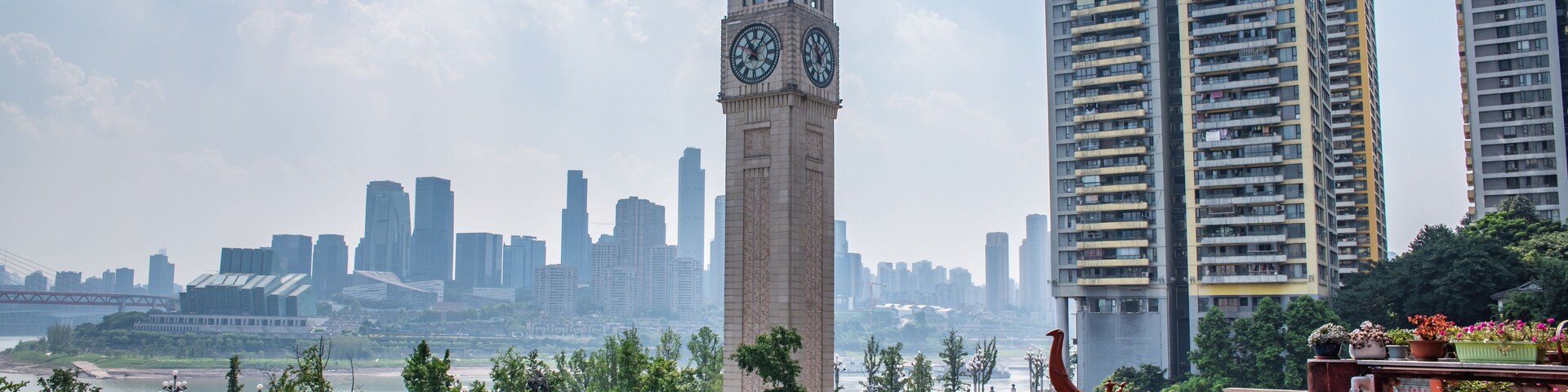 Una torre del reloj, modernos edificios altos y un río.