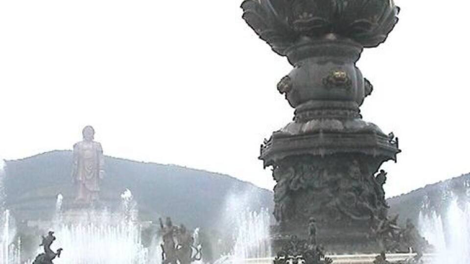 A large fountain with multiple statues and water jets, surrounded by a crowd of people.