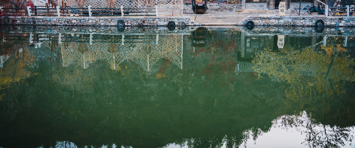 Dock by the river in Beijing WtownïŒGubei Water TownïŒ. Fishing boat moored by a river full of autumn leaves