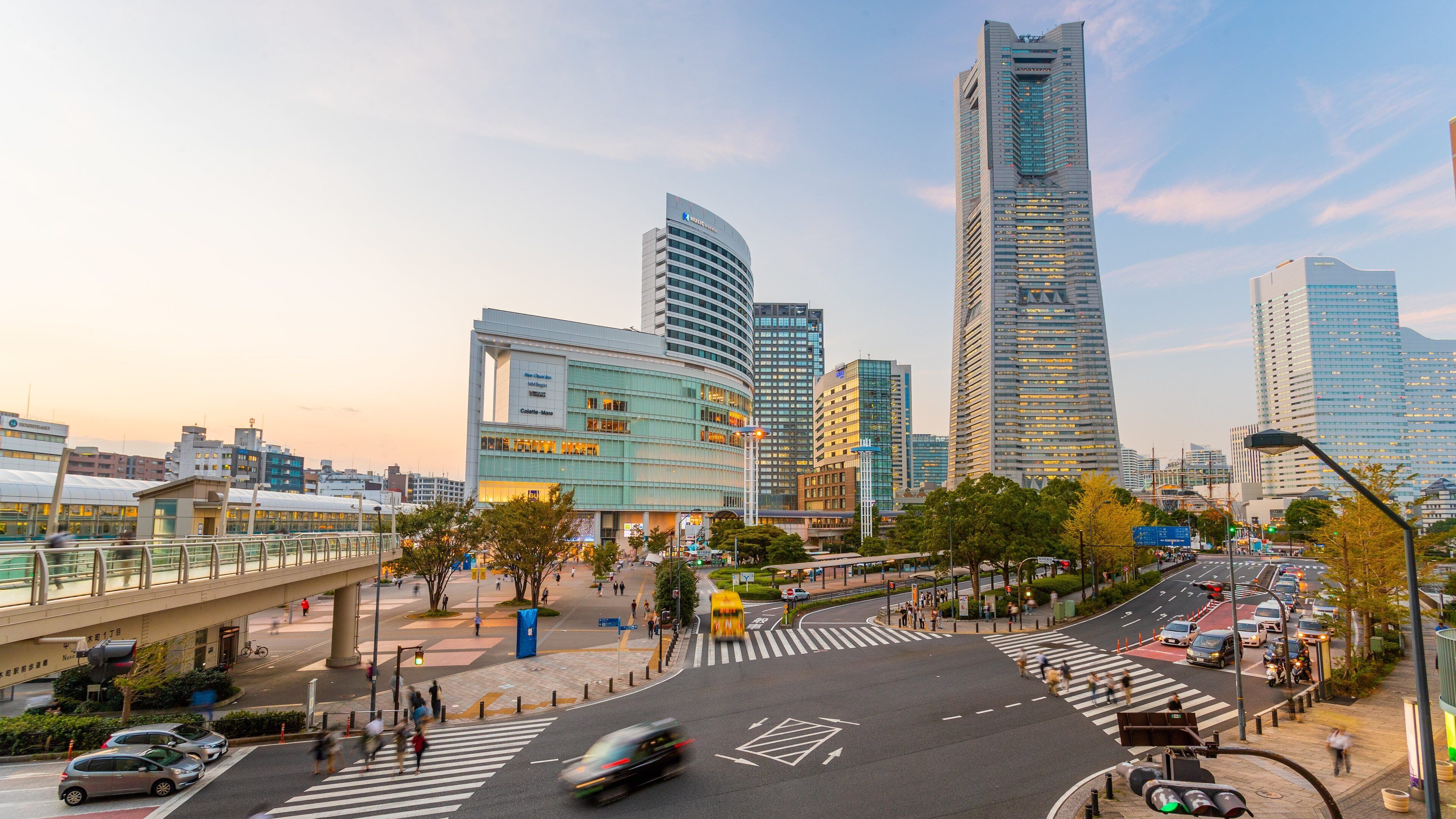 A cityscape with modern skyscrapers, a pedestrian bridge, and a busy intersection.