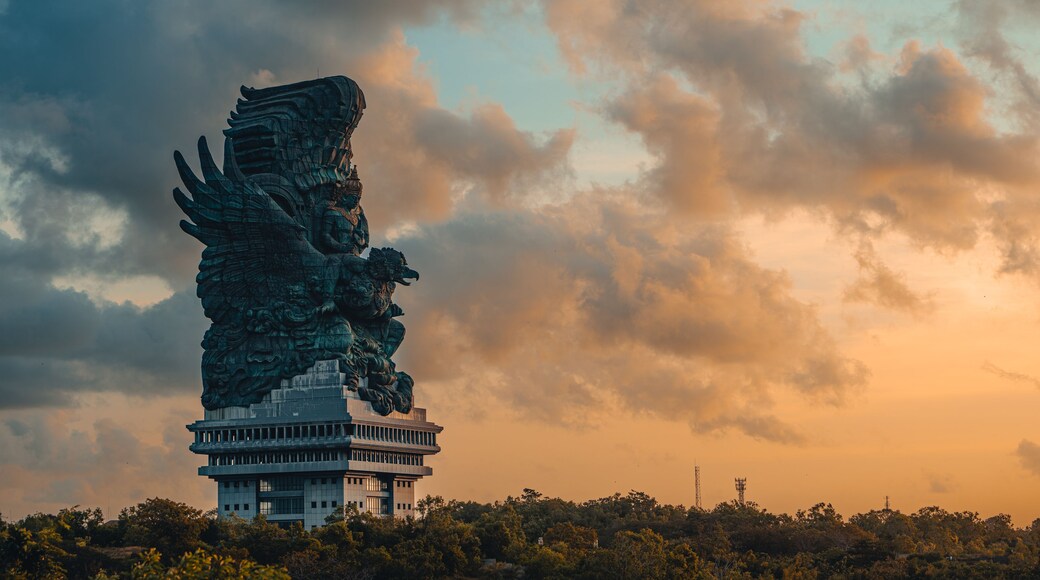 A large dragon statue atop a modern building, with a cloudy sky in the background.