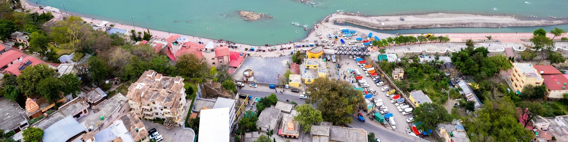 aerial drone shot over ram setu jhula suspension bridge with temples on the bank of river ganga in the holy spiritual city of Rishikesh Haridwar uttarakhand