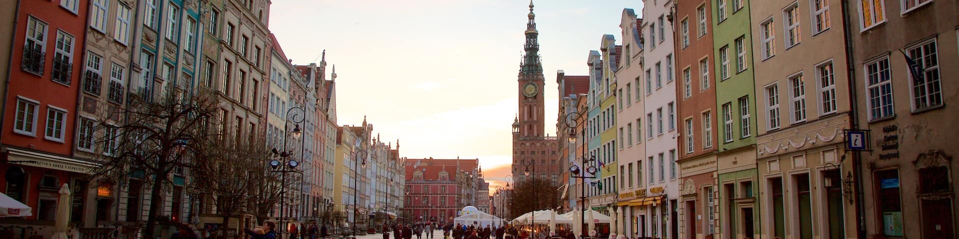 A cobblestone square with historic buildings and a prominent tower in the background.