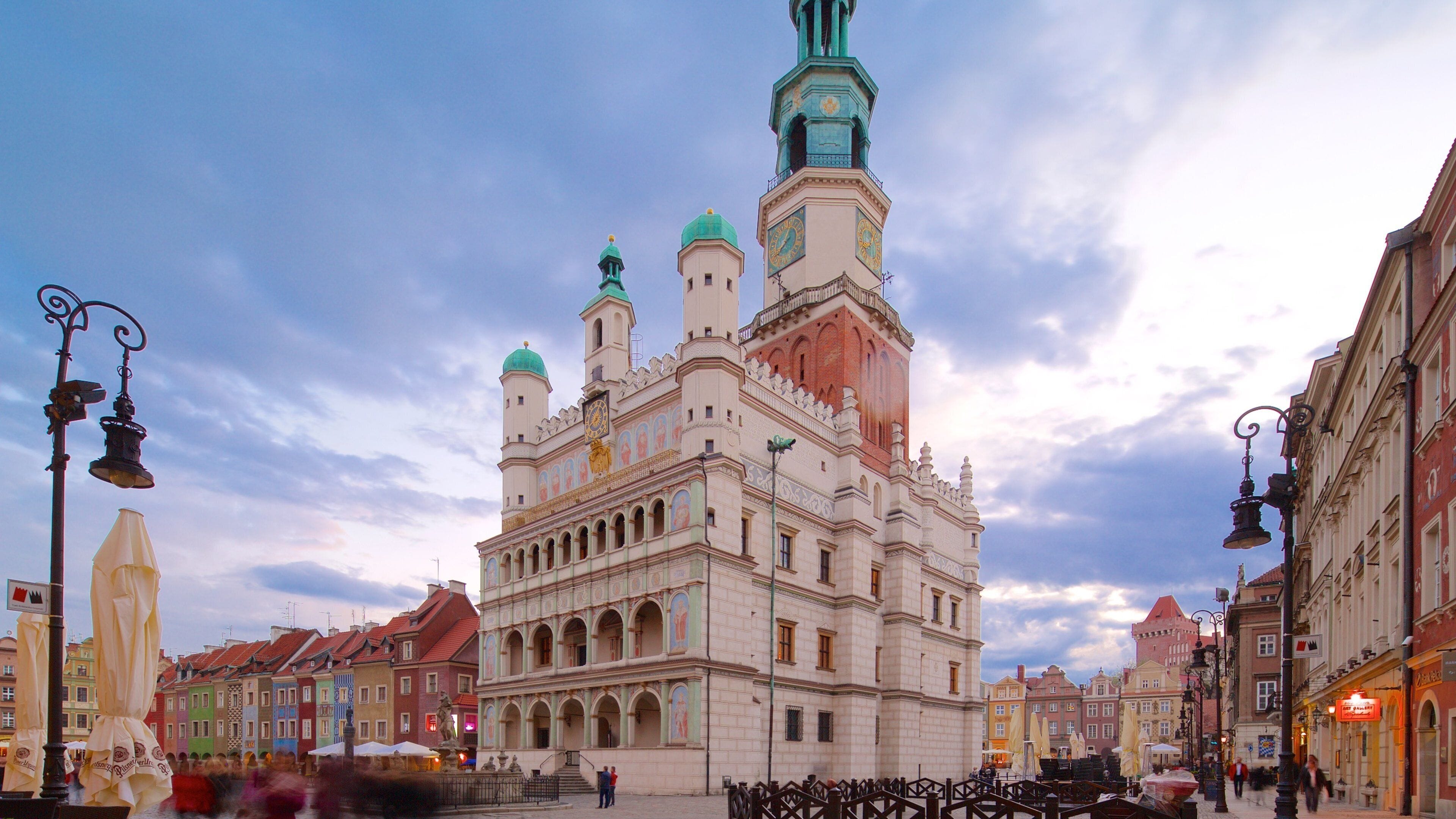 A historic building with multiple towers and a clock tower, surrounded by colorful buildings.