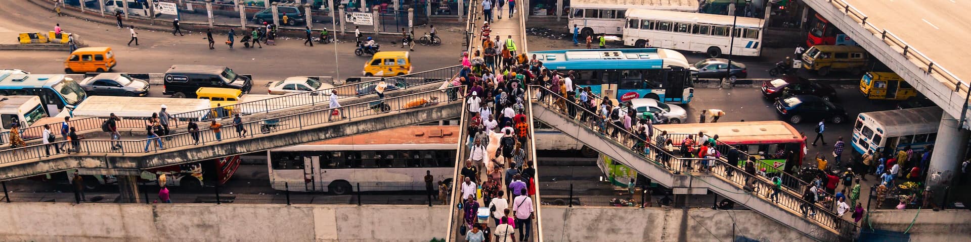 Lagos, Nigeria - 24 February 2026: Aerial view of the bustling Oshodi pedestrian overpass, teeming with people, vehicles, and vibrant city life under an expansive sky.
