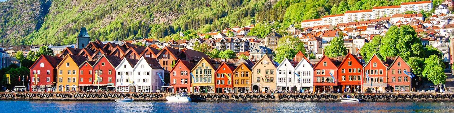 A waterfront town with colorful houses, a church, and a hill in the background.