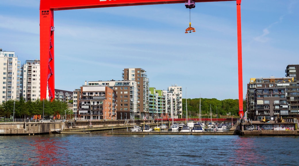 Un arco rojo con la inscripción 'ERIKSBERG', un puerto deportivo con barcos y edificios modernos al fondo.