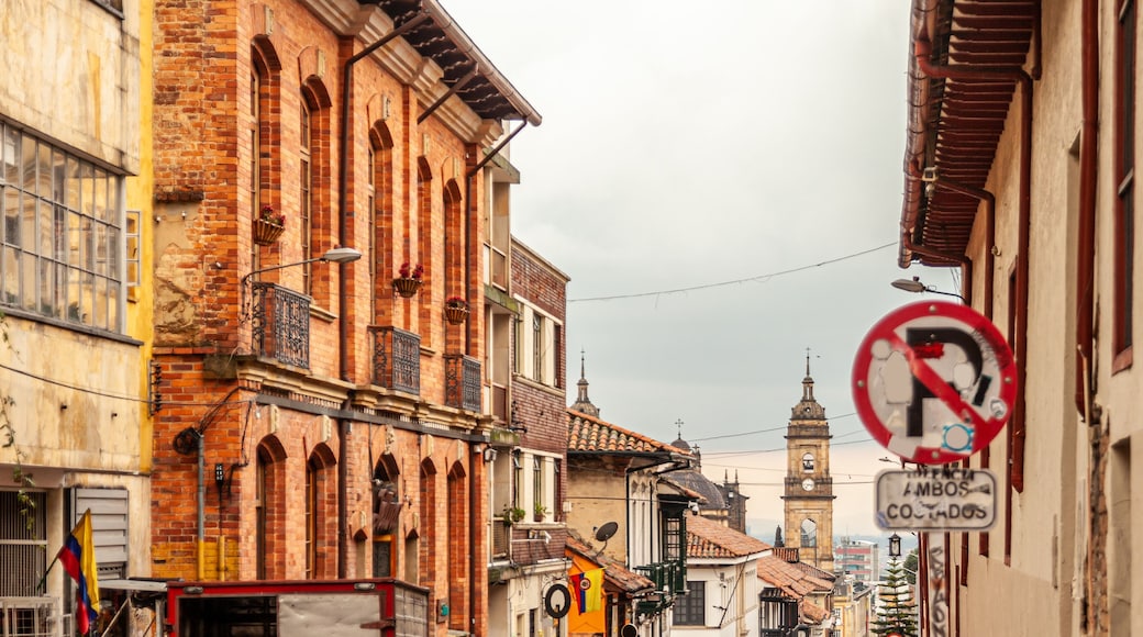 A narrow street lined with historic buildings, a no parking sign, and a clock tower in the distance.