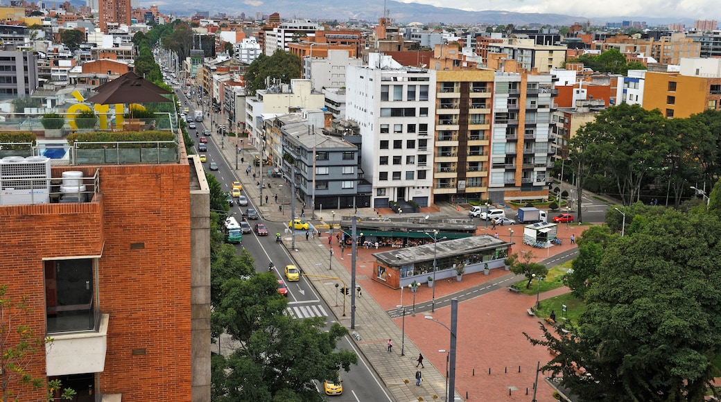 Un paysage urbain mêlant bâtiments modernes et plus anciens, une rue animée et des montagnes en arrière-plan.