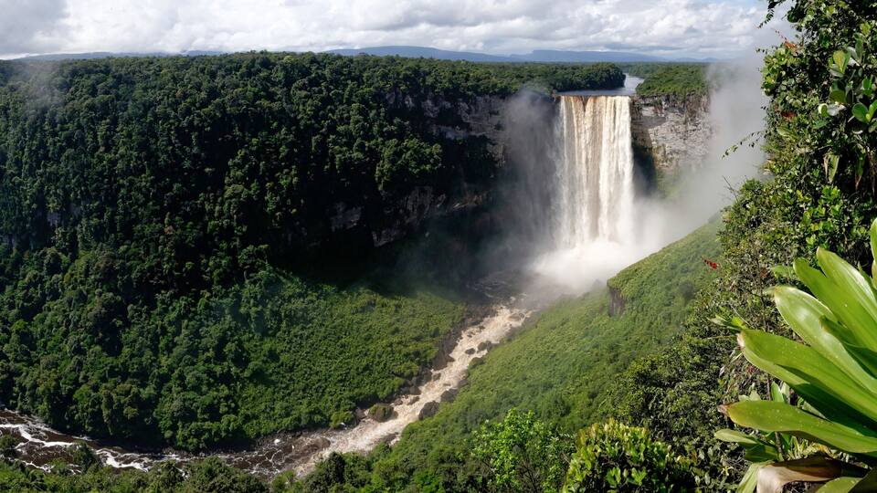 A large waterfall cascading down a lush green valley surrounded by dense forest.