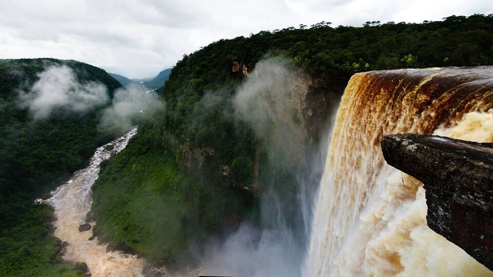 A large waterfall cascading down a cliff surrounded by lush green forest.