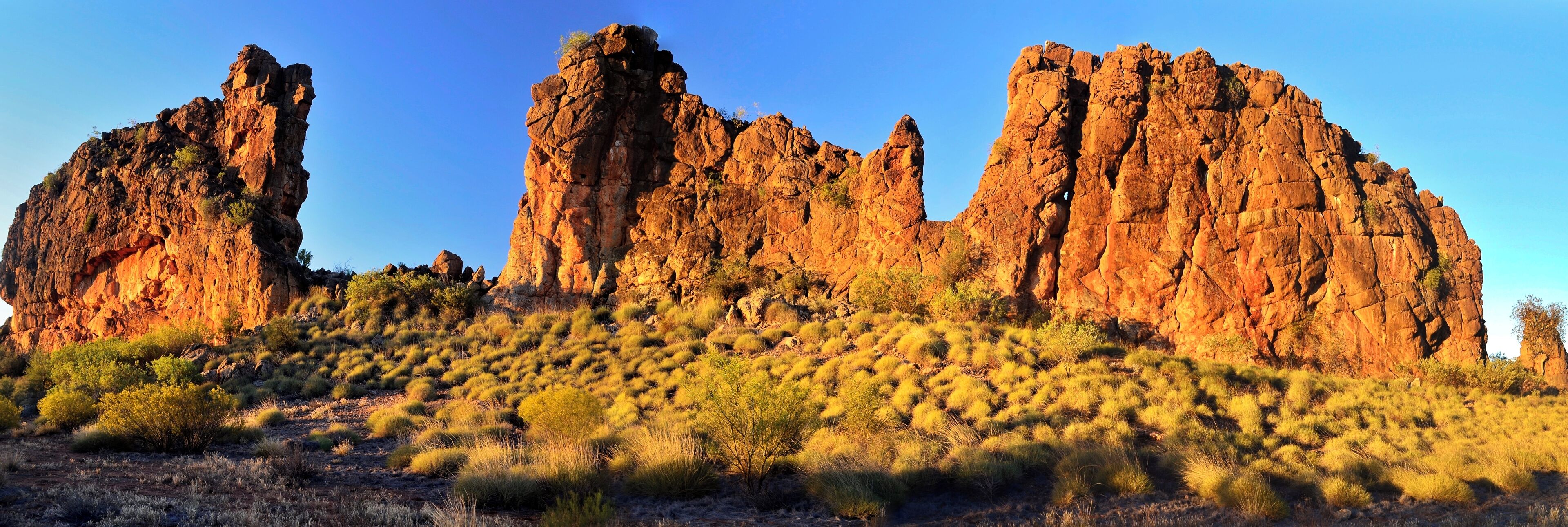 A desert landscape with prominent rock formations and sparse vegetation.