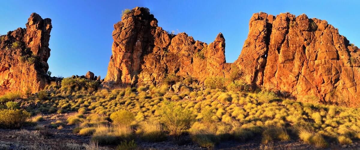 A desert landscape with prominent rock formations and sparse vegetation.