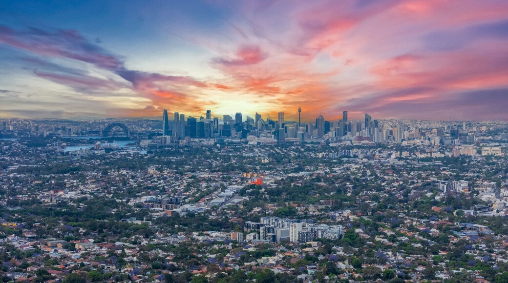 A city skyline with a sunset, featuring prominent skyscrapers and a dense residential area.