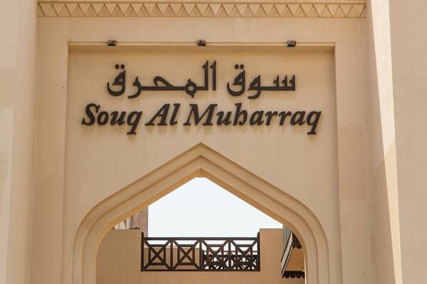 An entrance archway with the sign "Souq Al Muharraq" in Arabic and English.