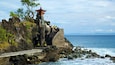 Un templo tradicional sobre un acantilado rocoso junto al mar, con una escalera que lo conduce.