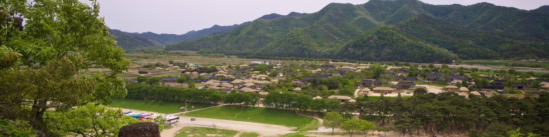 A river, a village with houses, and mountains in the background.