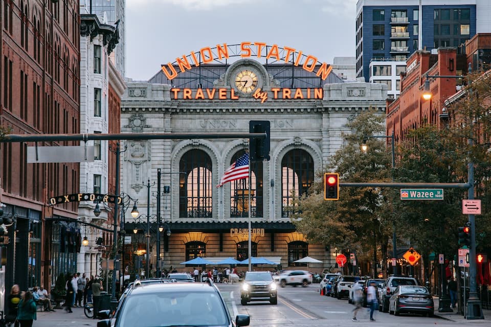 Union Station with a clock, American flag, and a street view with cars and pedestrians.