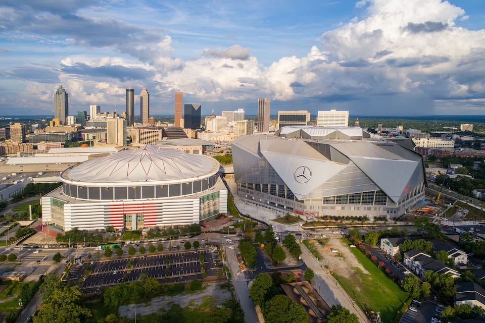 A city skyline with modern architecture, including a distinctive building with a Mercedes-Benz logo.