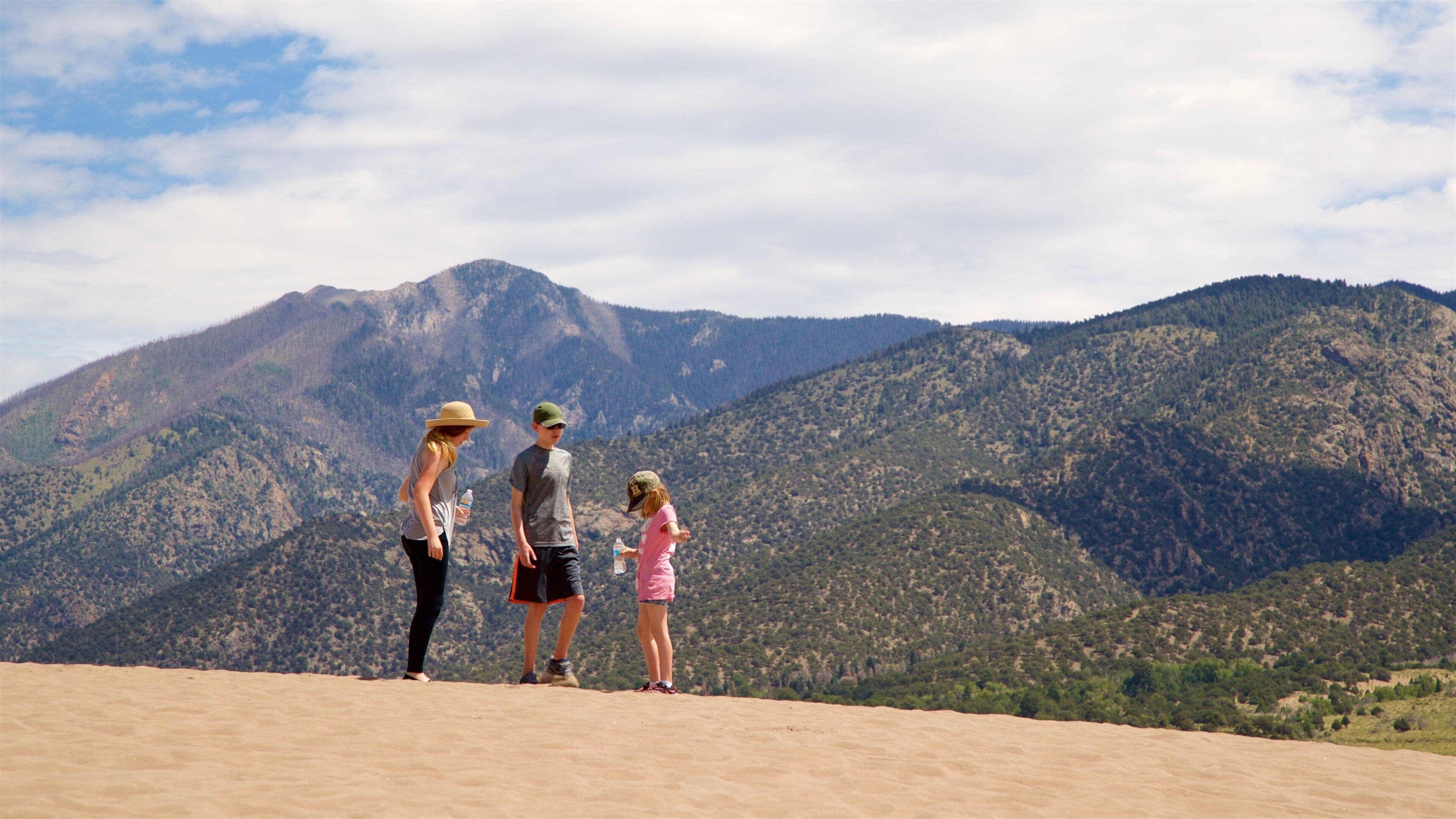 A family standing on a sandy hill with a mountainous landscape in the background.