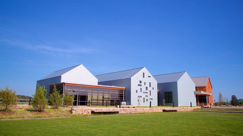 A modern building with a glass facade and a stone base, set against a clear blue sky.