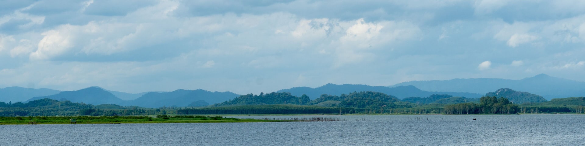 Horizontal view of river or reservoir
of Prasae Wang Chan of Rayong. Background of mountain far the way. Under the sky and white clouds.