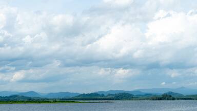 Horizontal view of river or reservoir
of Prasae Wang Chan of Rayong. Background of mountain far the way. Under the sky and white clouds.