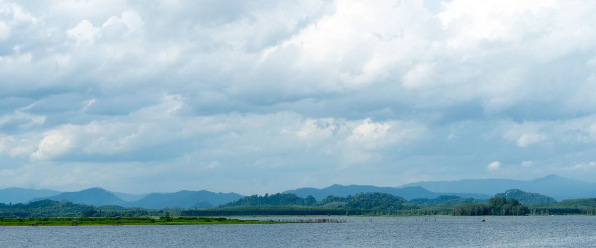 A lake with mountains in the background and a cloudy sky.