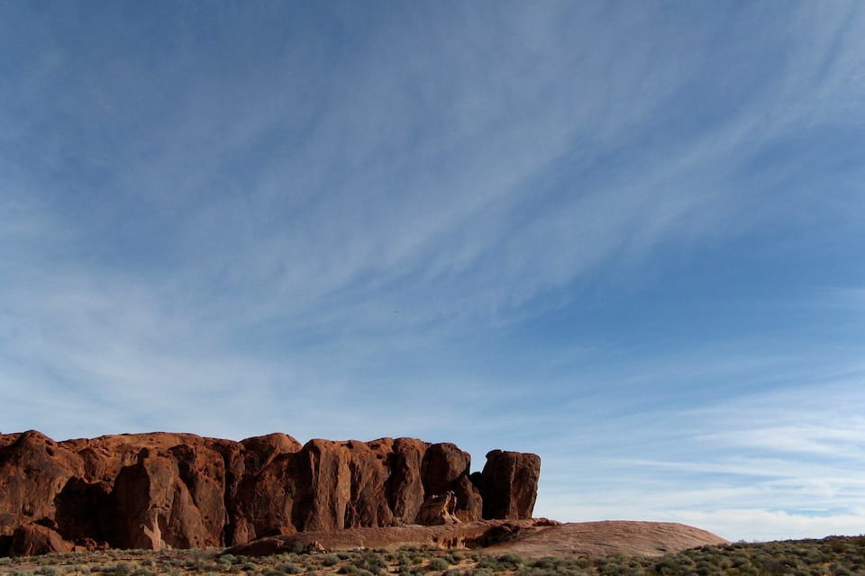 A desert landscape with prominent red rock formations under a clear sky.