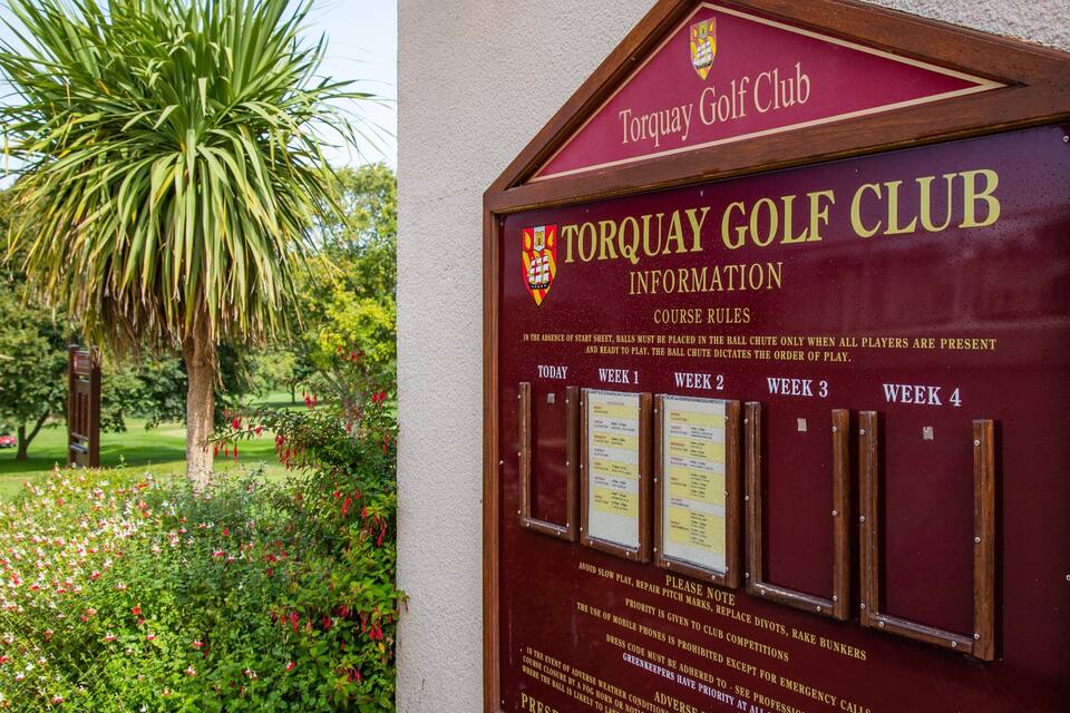 A Torquay Golf Club sign with information and course rules.